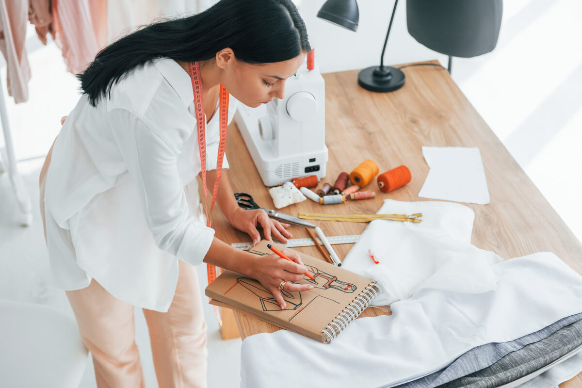 busy-at-work-seamstress-is-in-her-office-that-is-XUUEE6W Baixe o Catálogo de Uniformes ProfissionaisAttelier Visual
